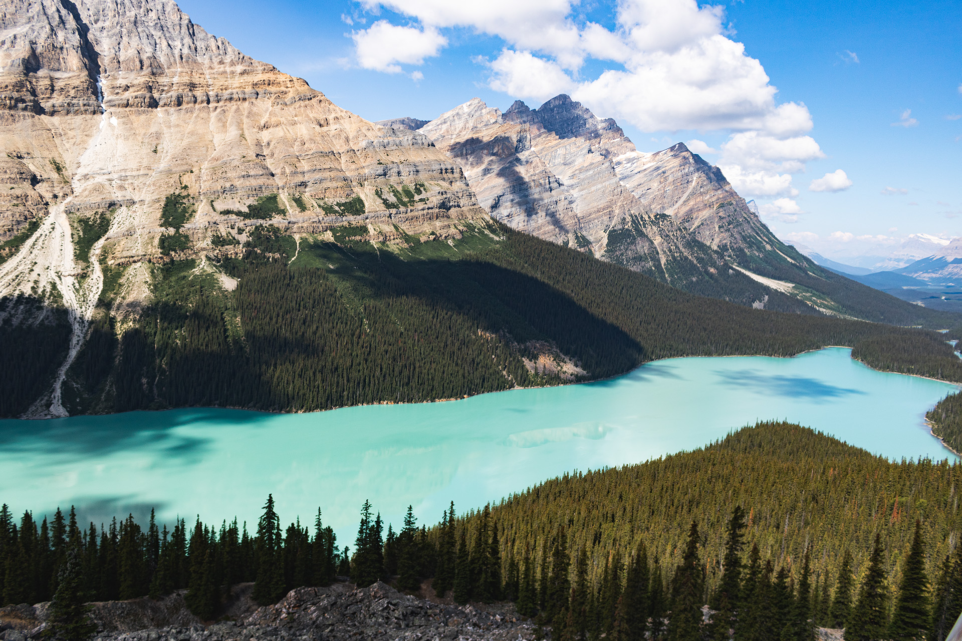 Rocky mountains overlooking a blue lake, seen from halfway up the mountain's height.